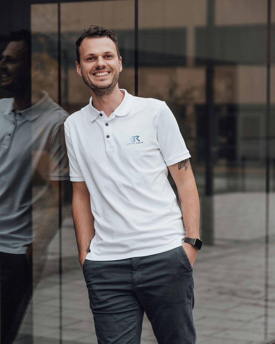 Dominik Mayr, Inhaber von WorkEasy, lächelt in ein weißes Poloshirt gekleidet vor einer Glasfassade